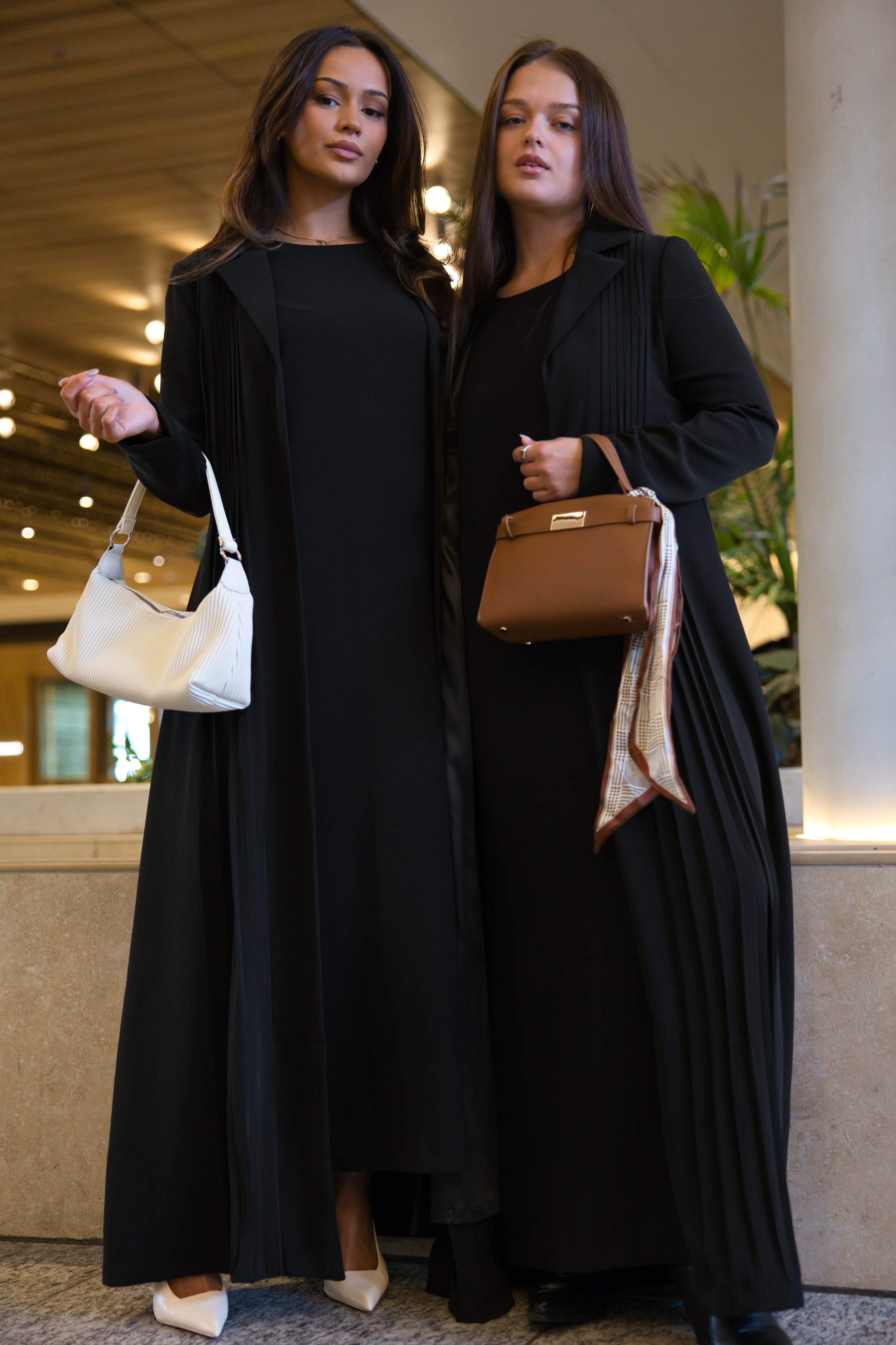 Models showcase the Amani pleated blazer set in black, paired with structured handbags and modest styling in a refined lifestyle setting